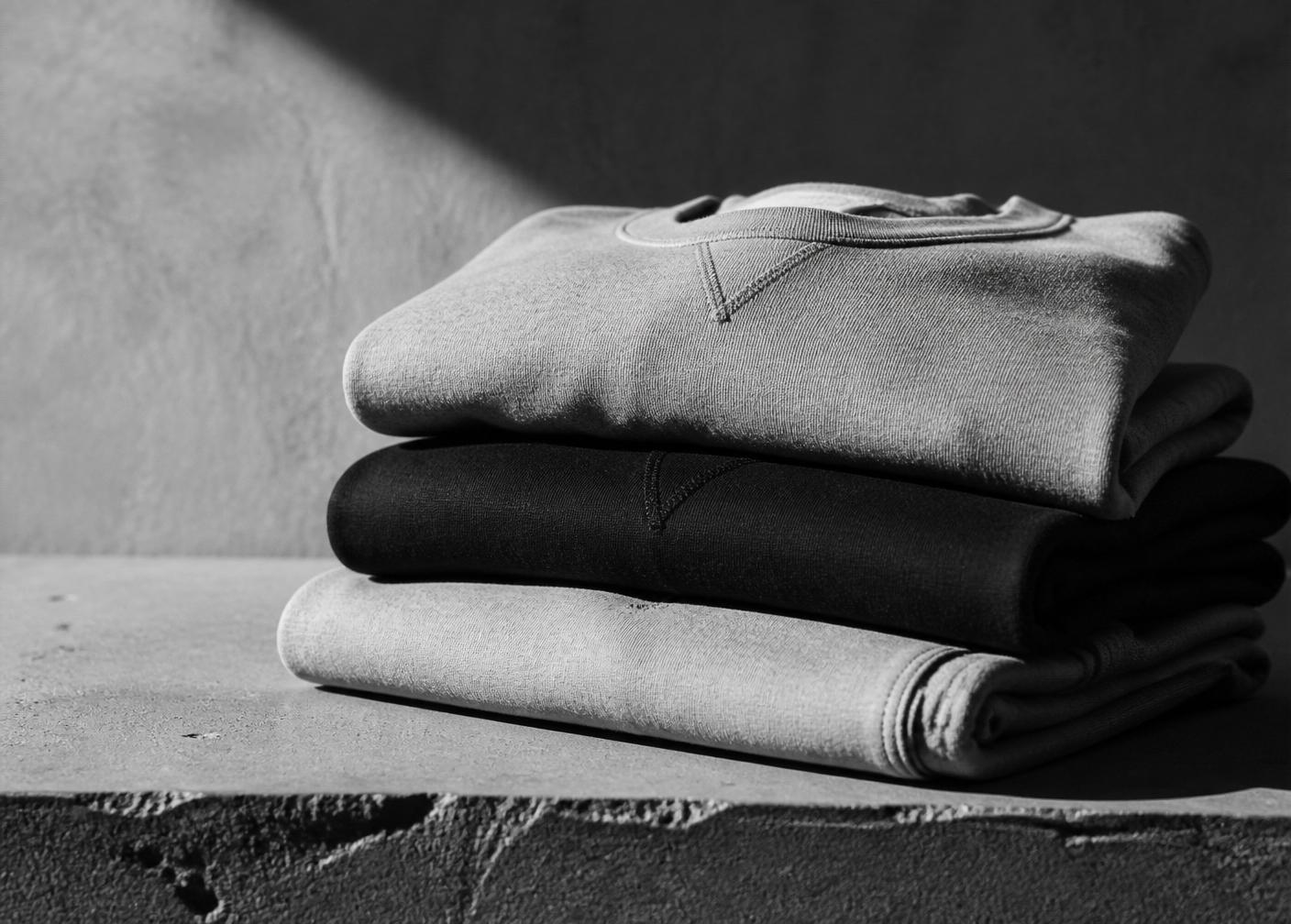 Stack of folded heavyweight Imago Dei garments on concrete